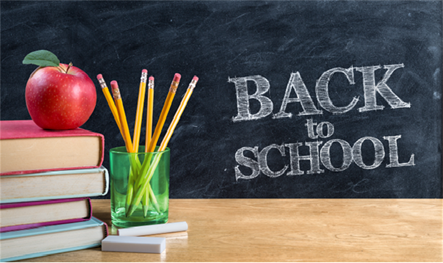 Back to school written on a blackboard with an apple stacked on books and pencils in a cup next to chalk on a table